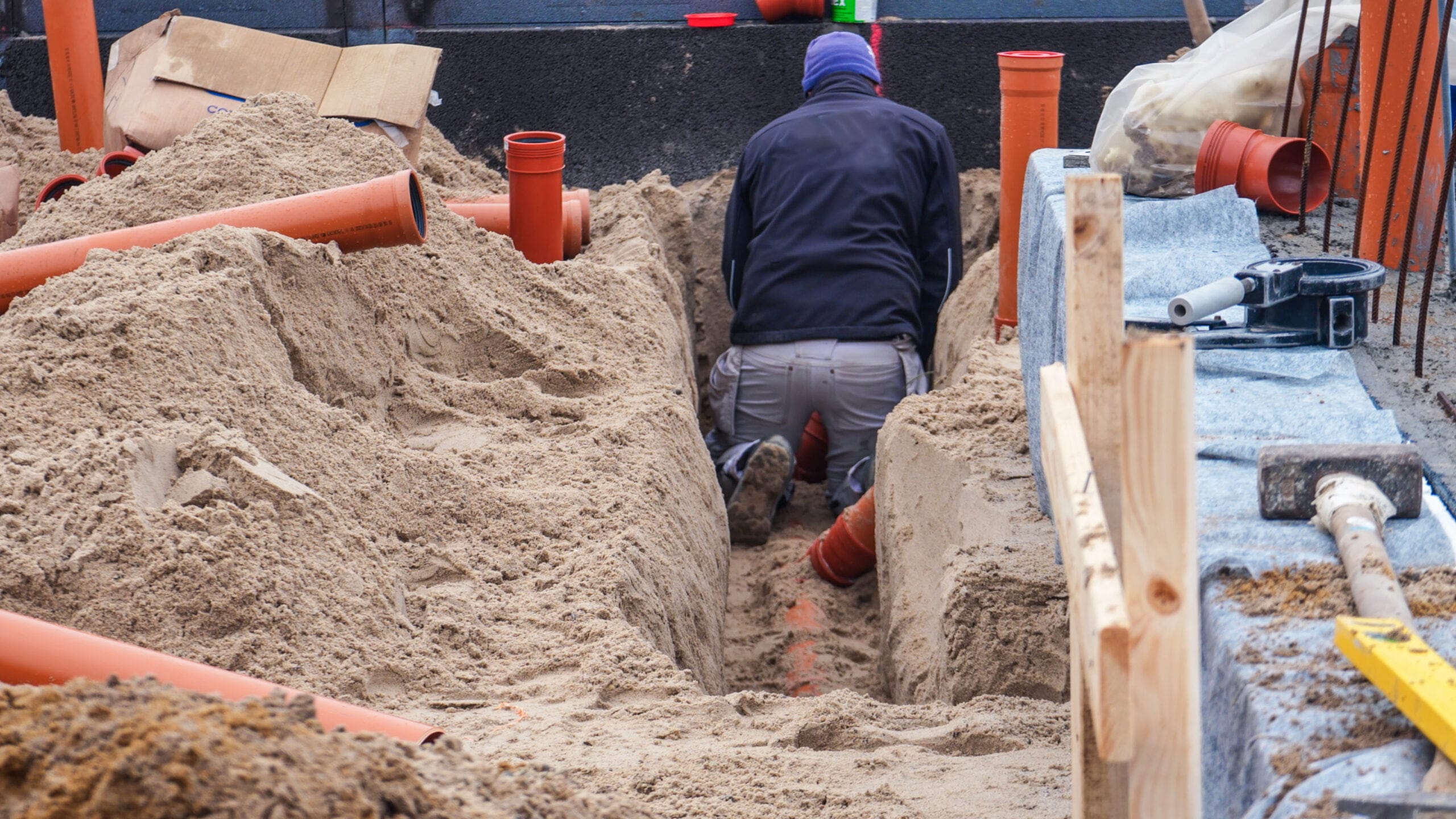 Arbejder installerer kloakrør i byggeudgravning