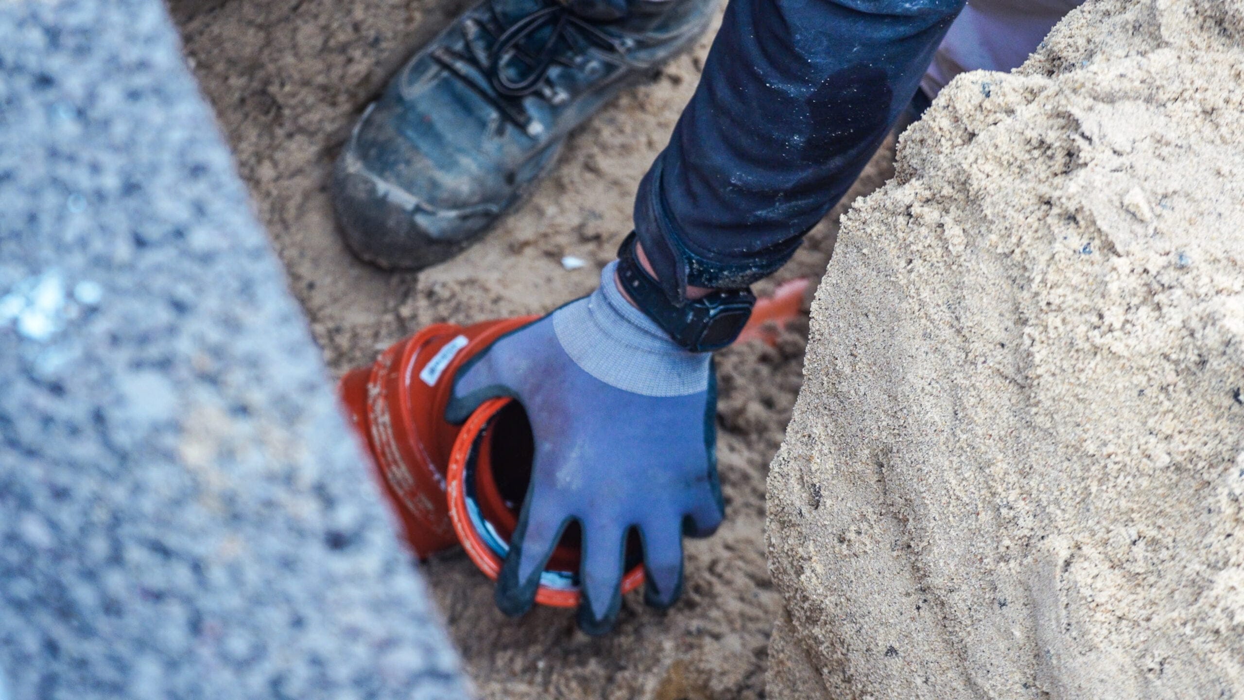 Arbejder installerer orange rør i sandet