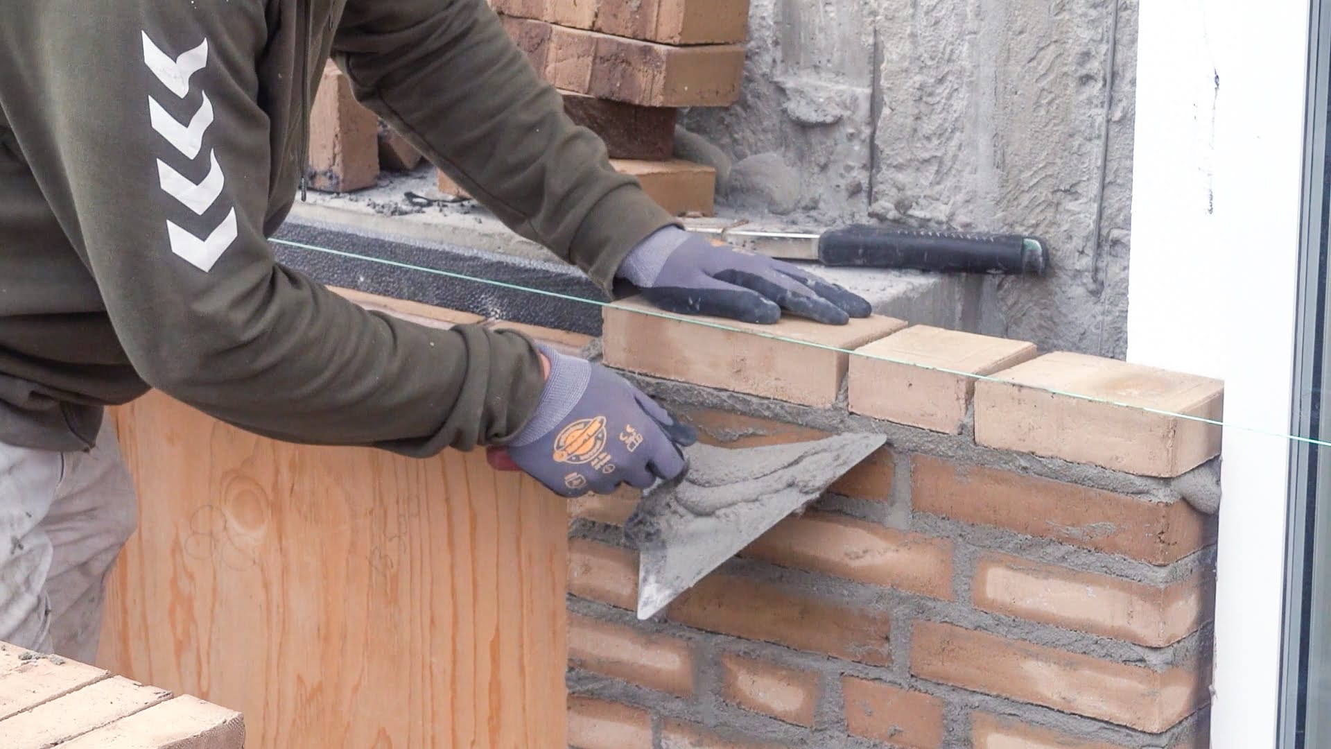 Murermester lægger mursten med mørtel