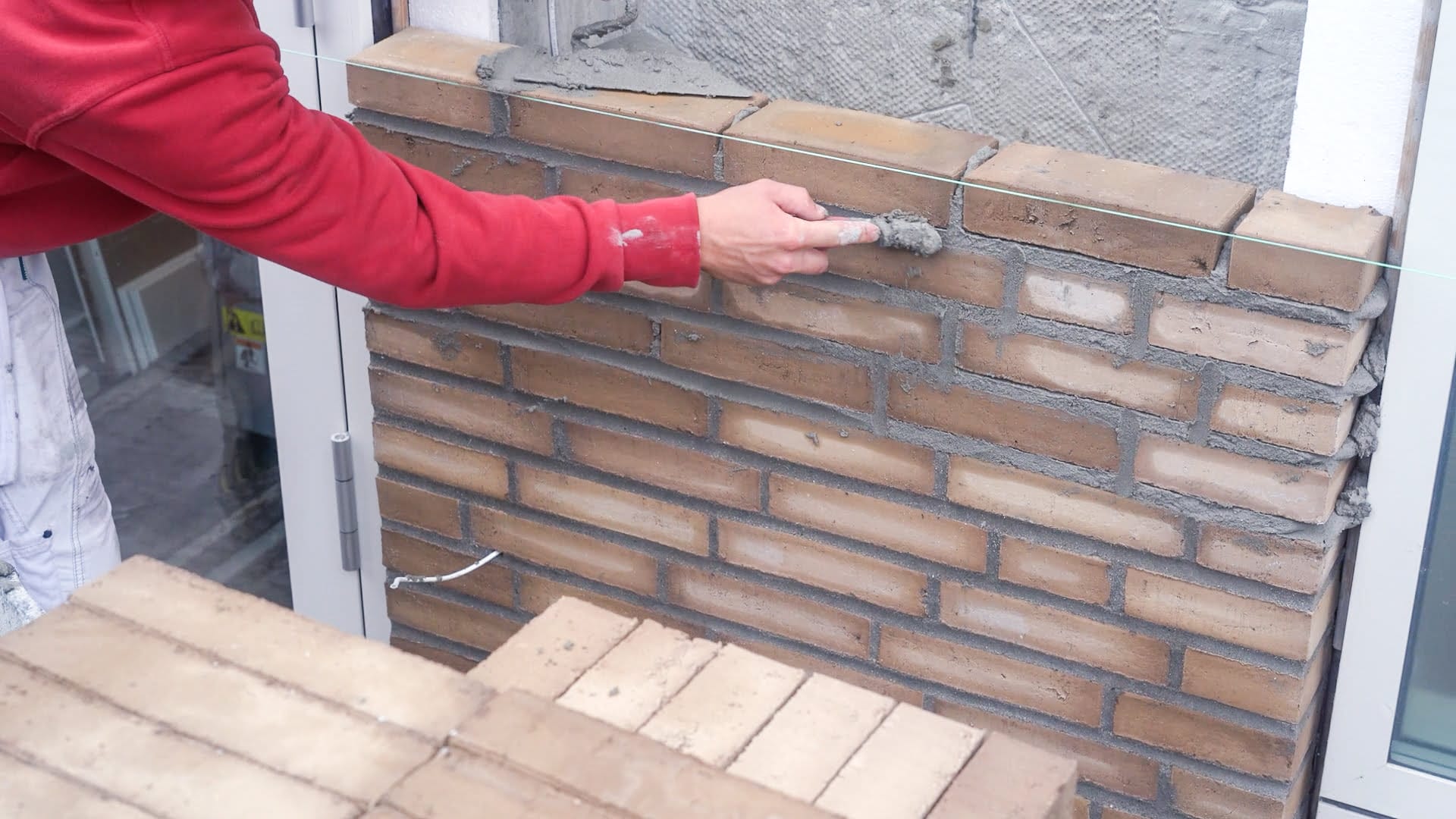 Murarbejder fuger murstensvæg med mørtel