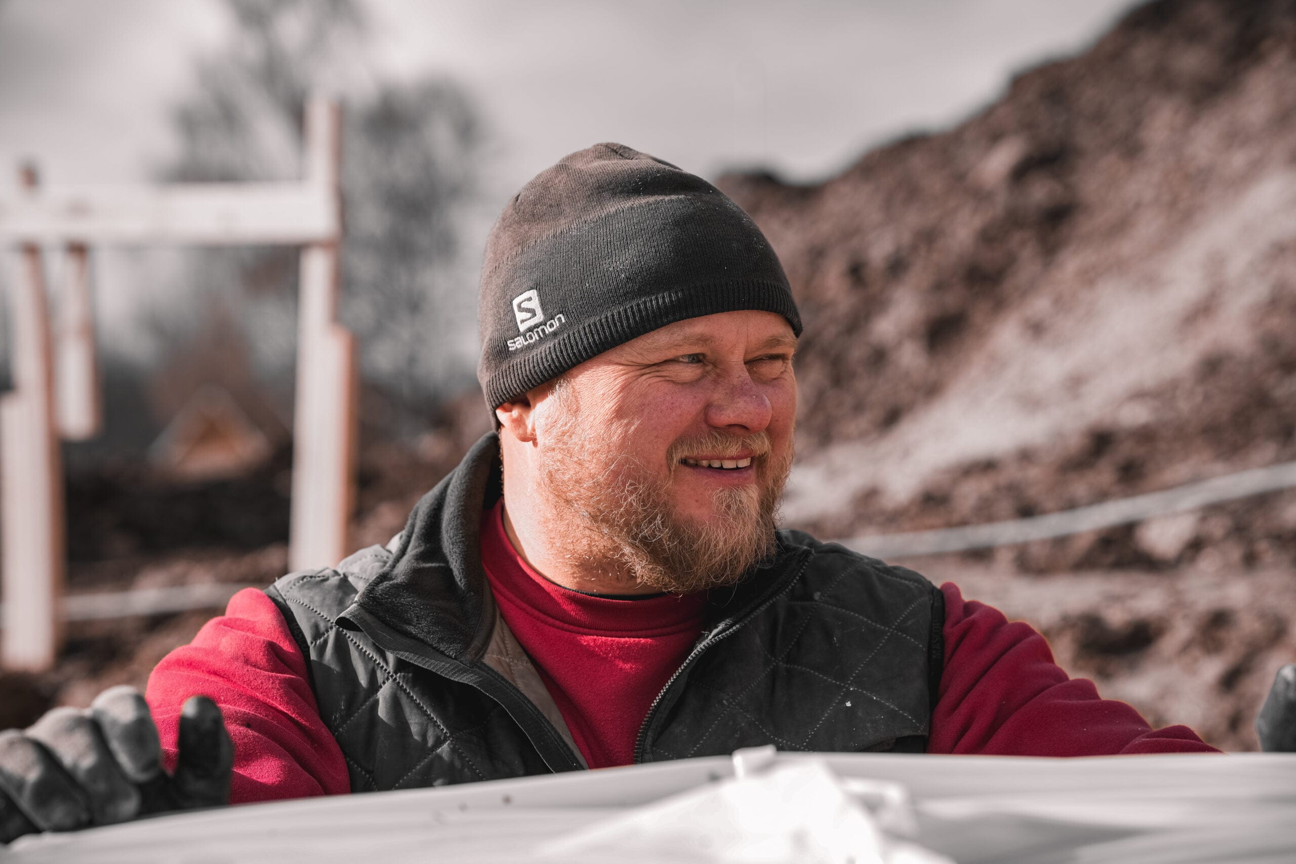 Mand arbejder udendørs iført hue og arbejdsvest