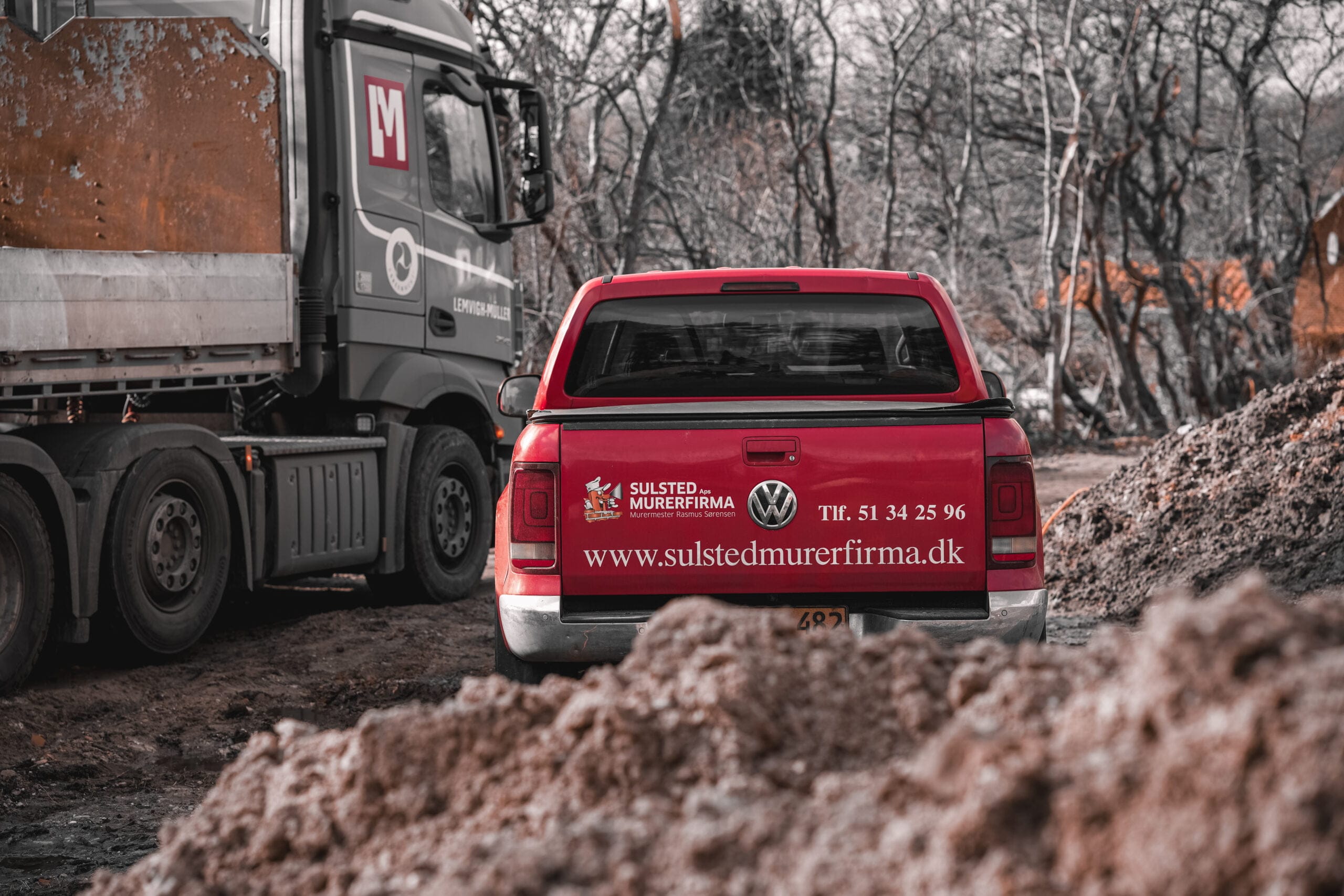 Rød varevogn fra murerfirma på byggeplads