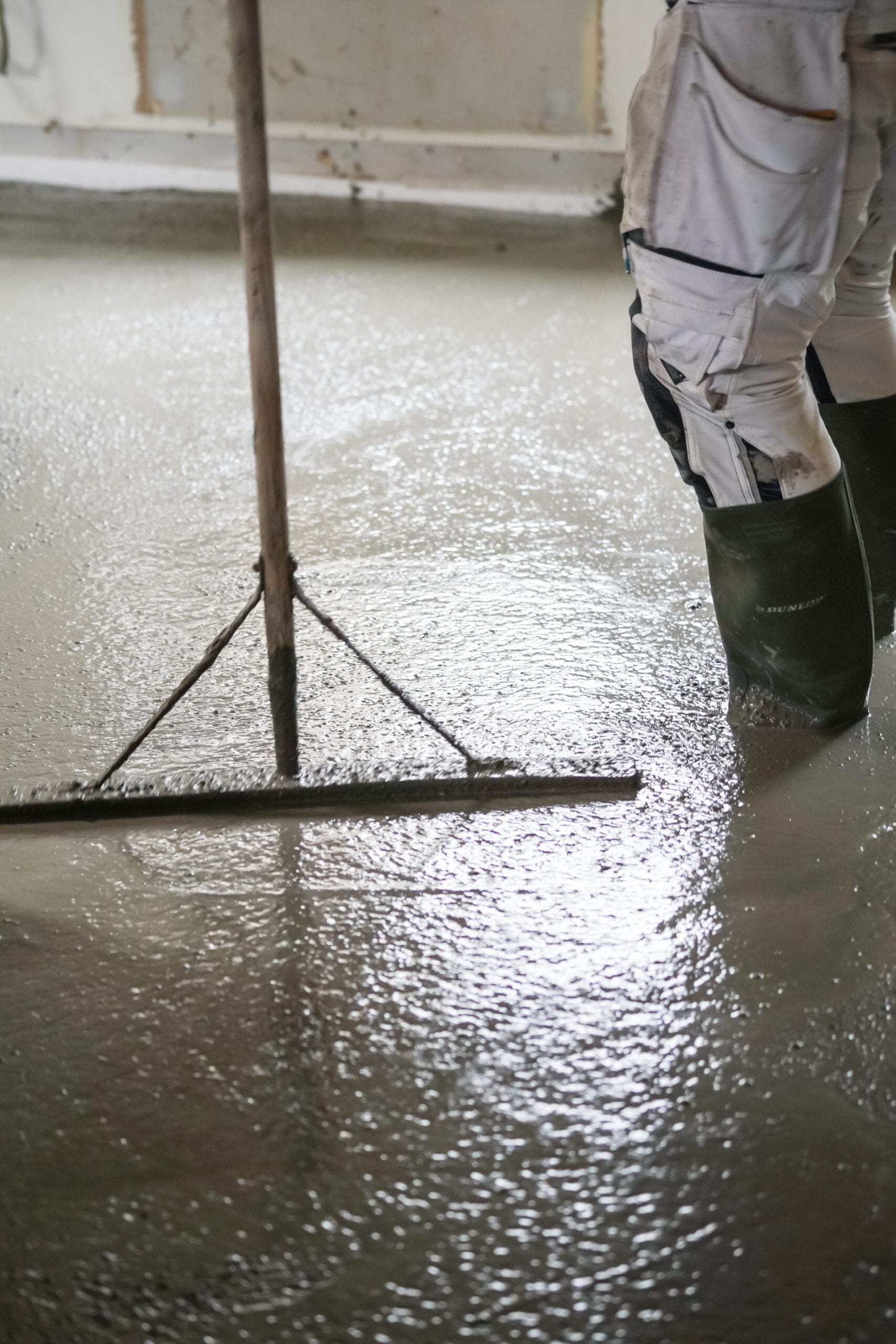 Arbejder udjævner vådt betongulv med værktøj