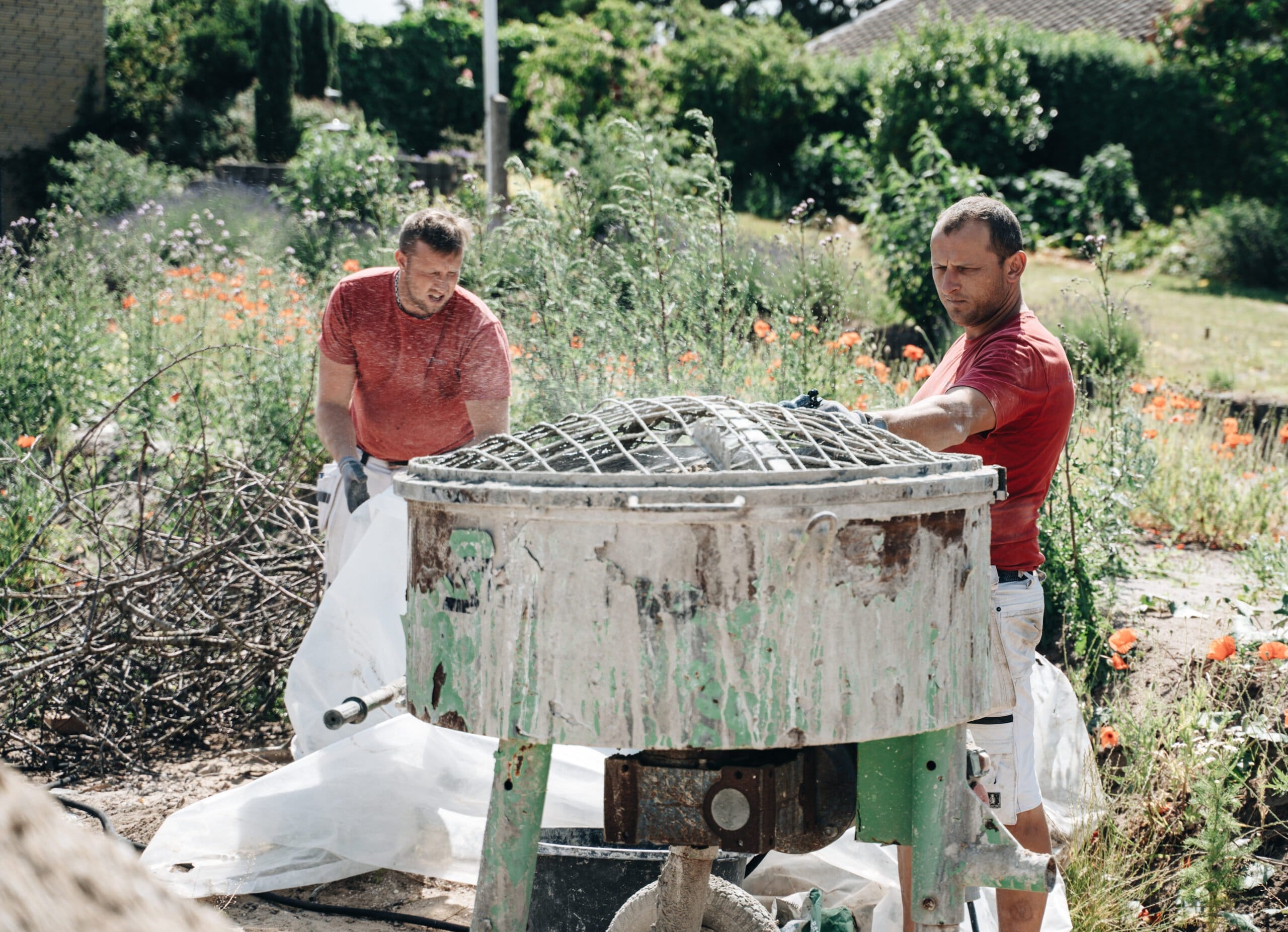 To mænd arbejder ved cementblander udendørs