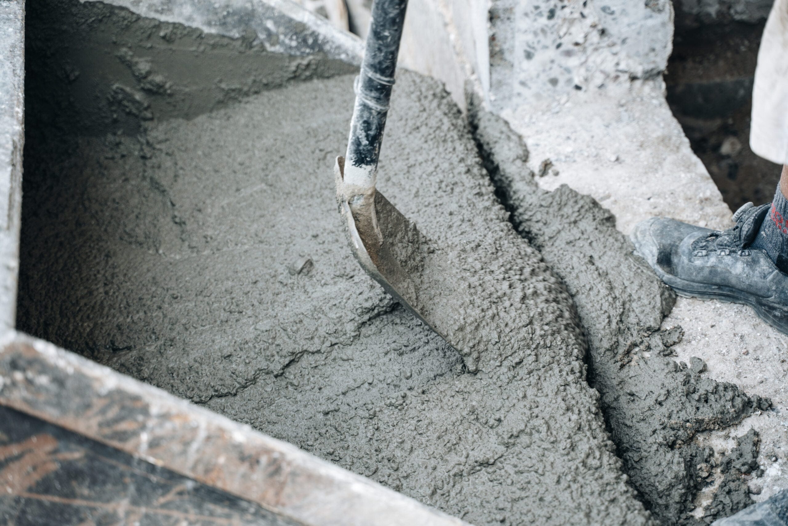 Arbejdskraft blander frisk beton med skovl