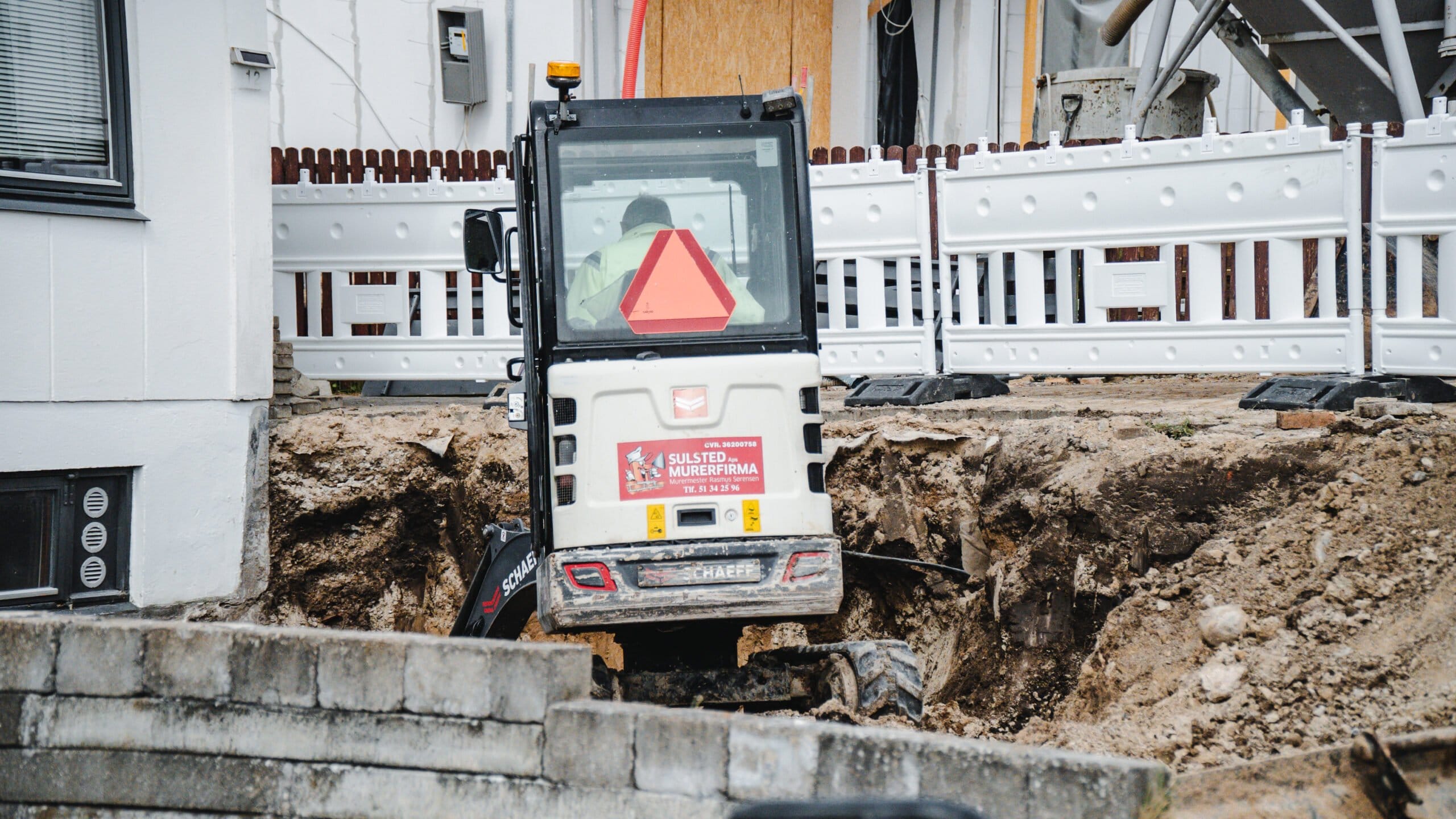 Gravemaskine arbejder på byggeplads ved hus