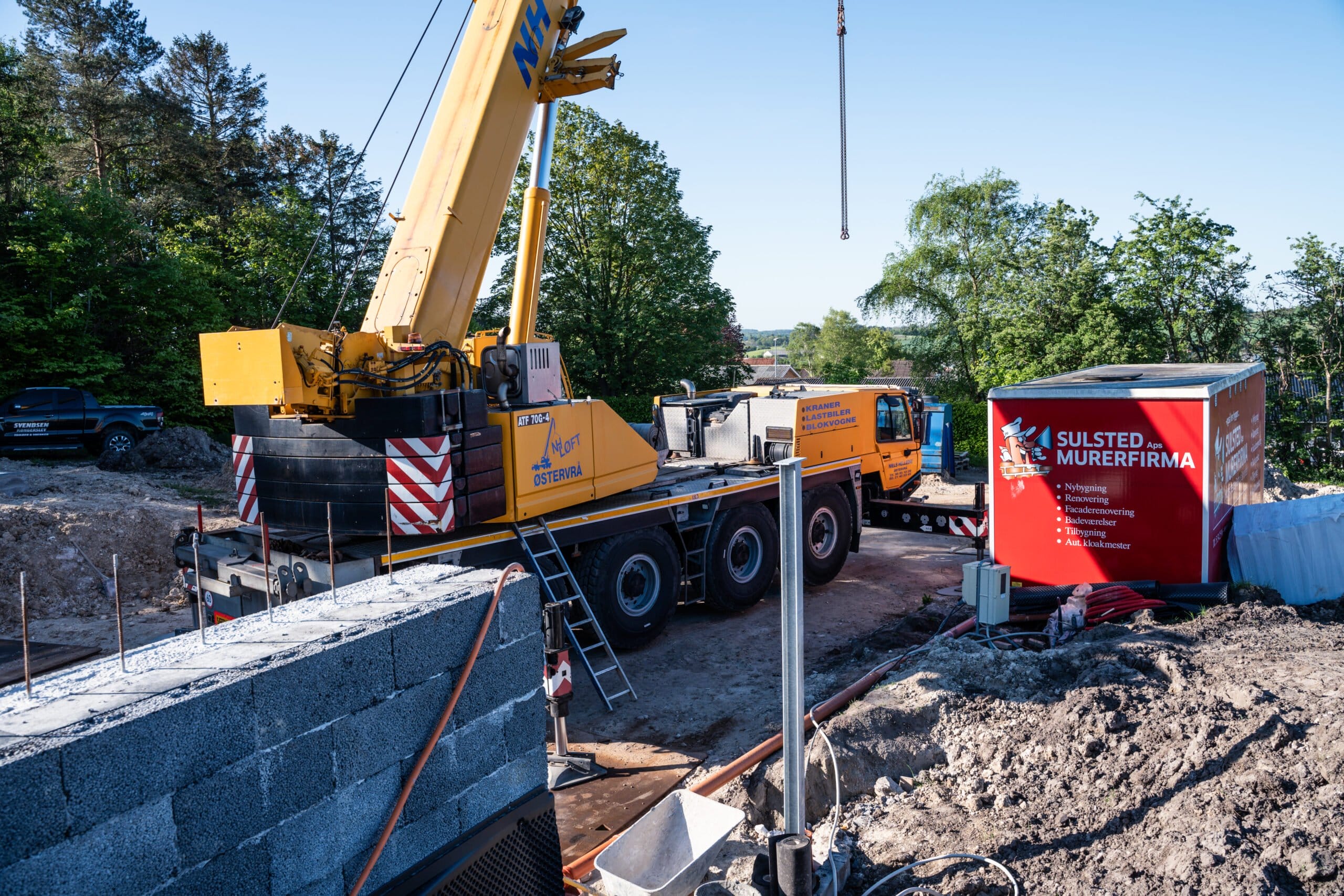 Byggeplads med kran og murermaskiner i arbejde