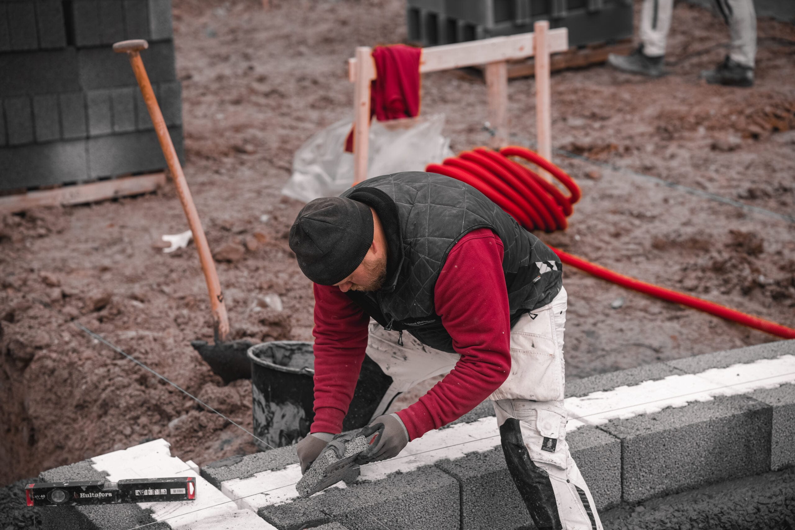 Murer arbejder på byggeplads med mursten