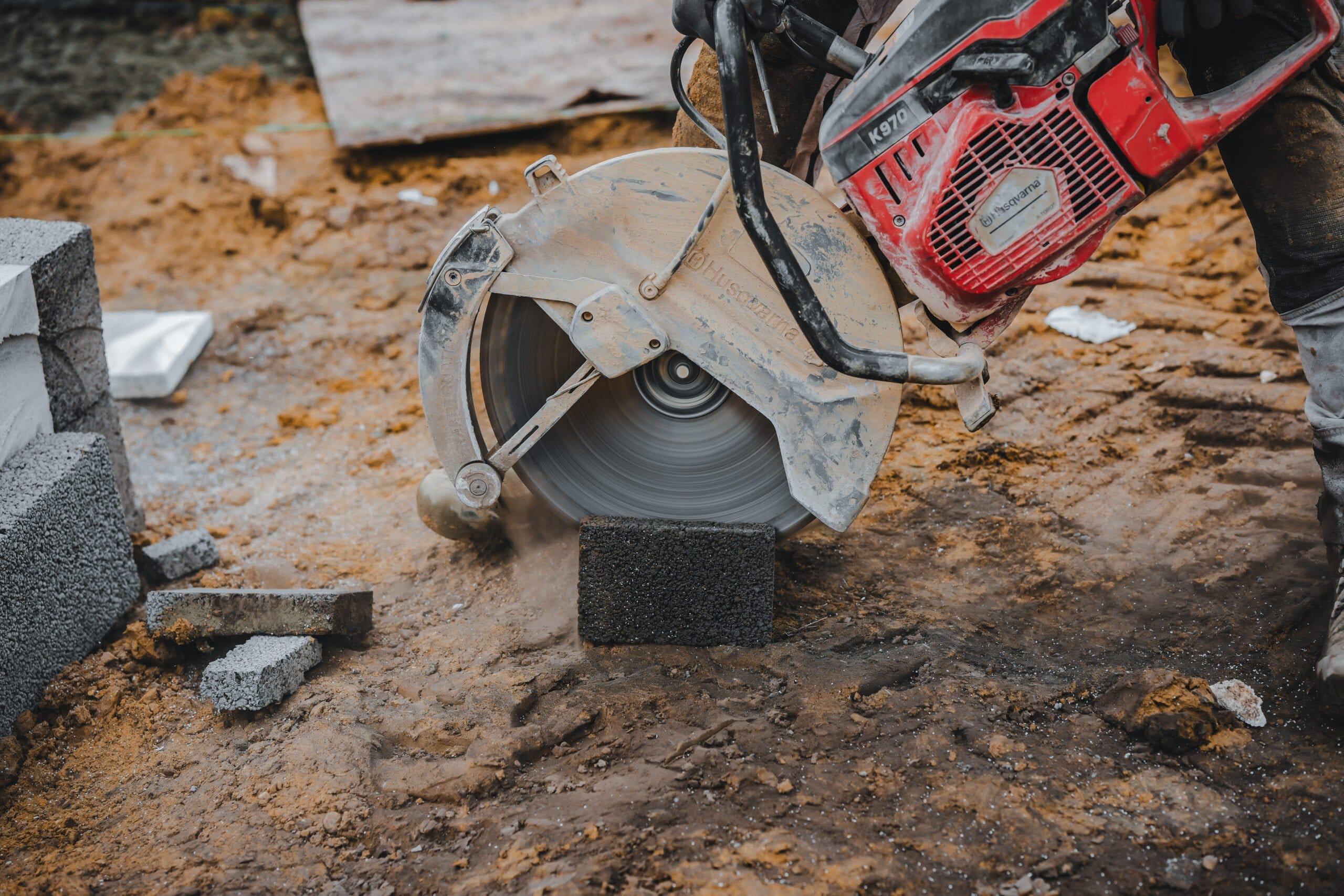 Arbejder skærer betonblok med rundsav på byggeplads