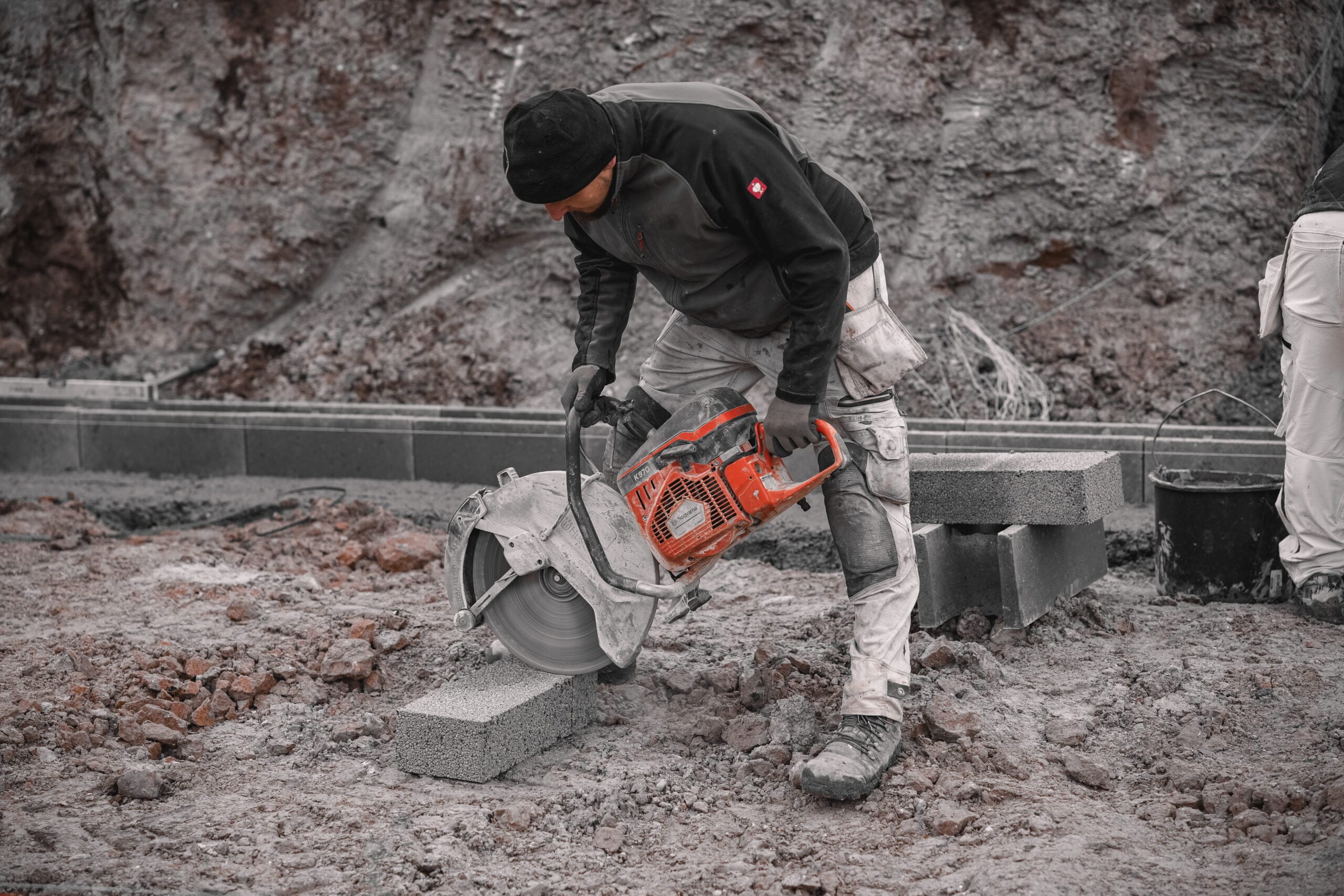 Arbejder skærer betonblok med rundsav på byggeplads