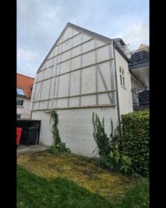 Hus med afdækket facade og klatreplanter i gård