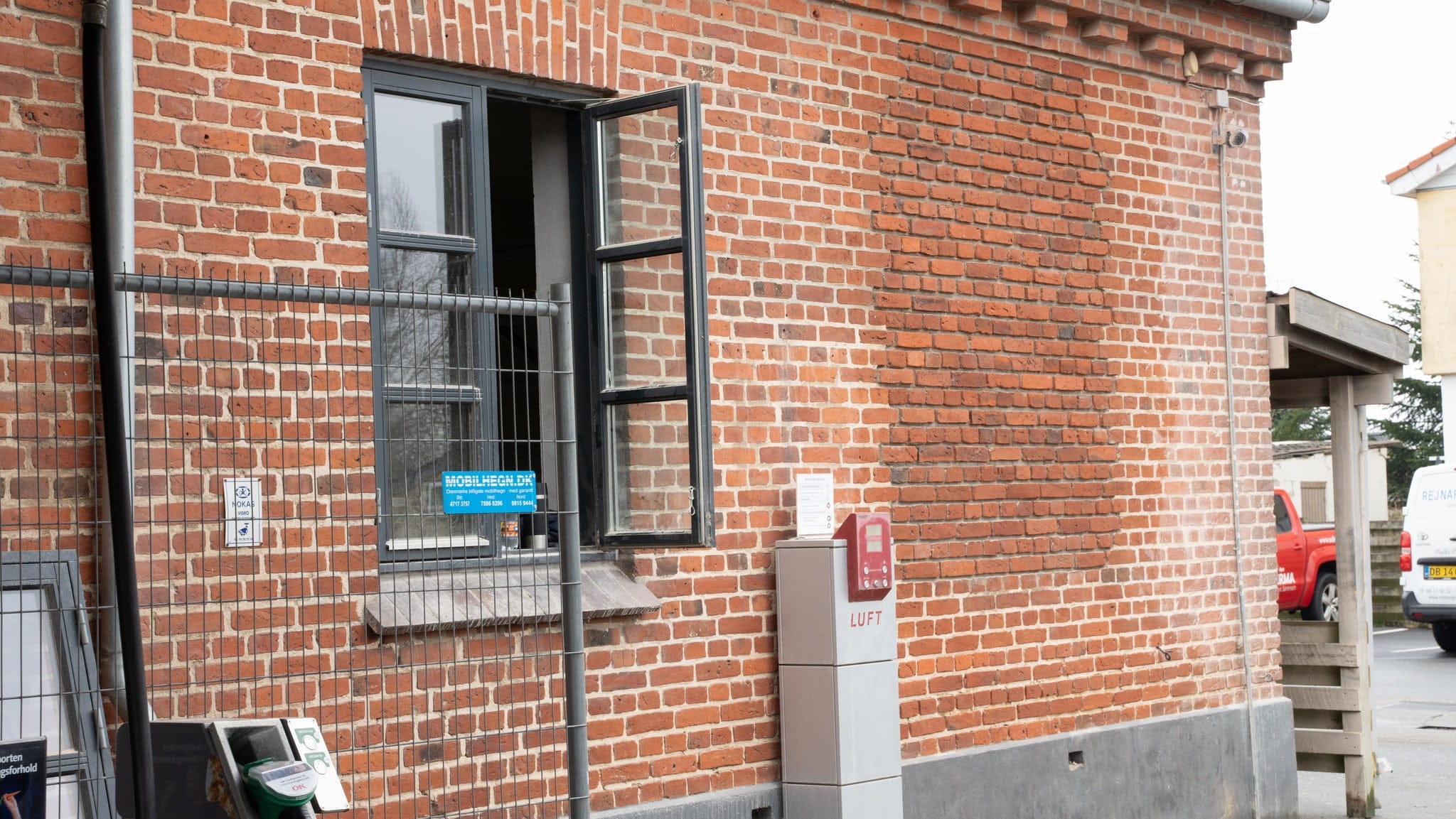 Murstensbygning med åbent vindue og luftstation