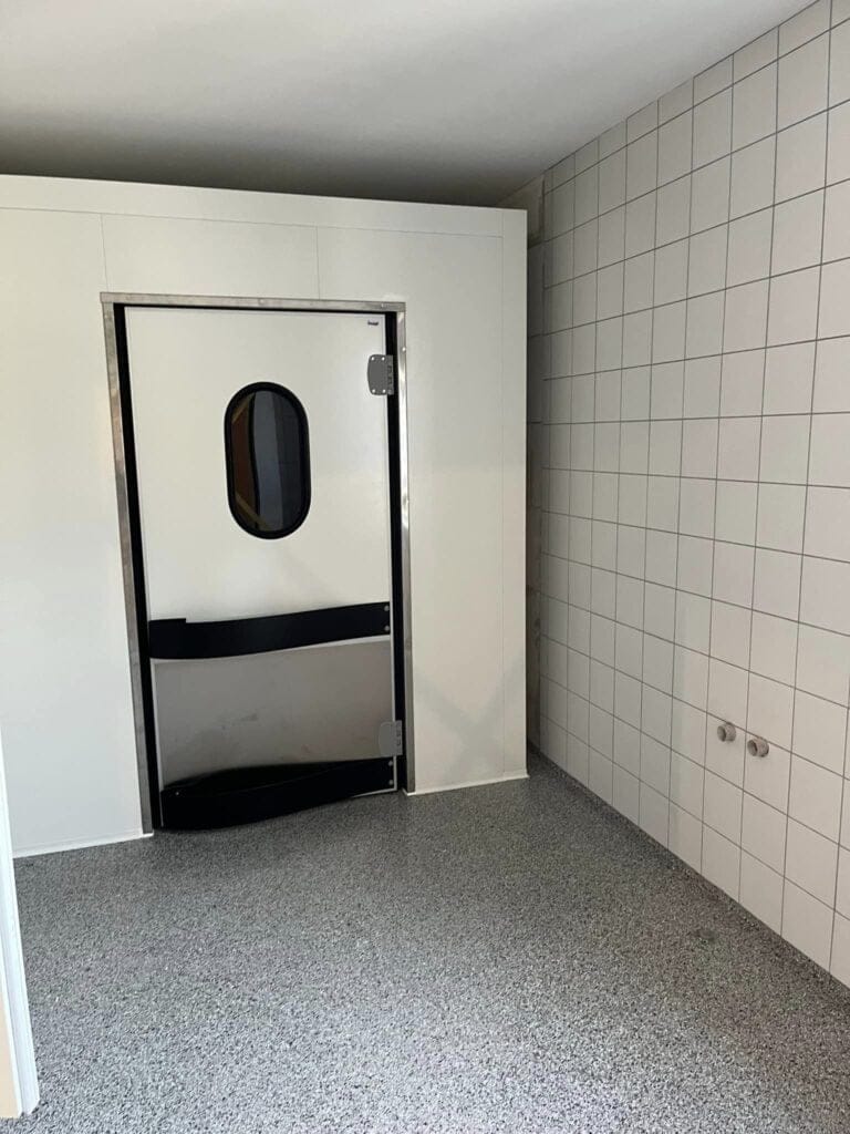 Industridør i rum med flisevæg og grå gulv