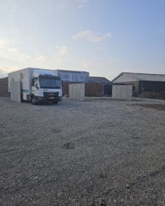 Lastbil parkeret på grusplads ved industribygninger