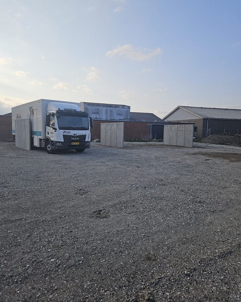 Lastbil parkeret på grusplads ved industribygninger