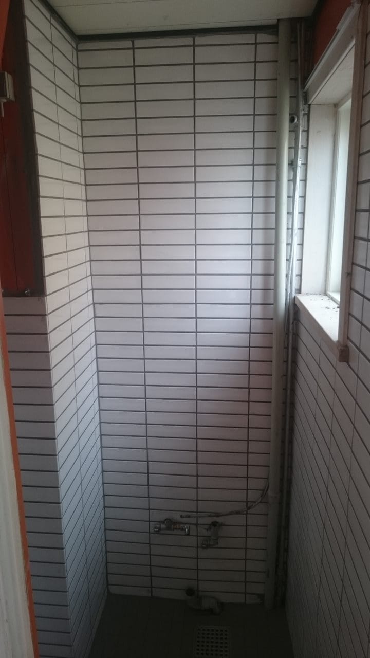 Ufærdigt badeværelse med hvide fliser og vindue